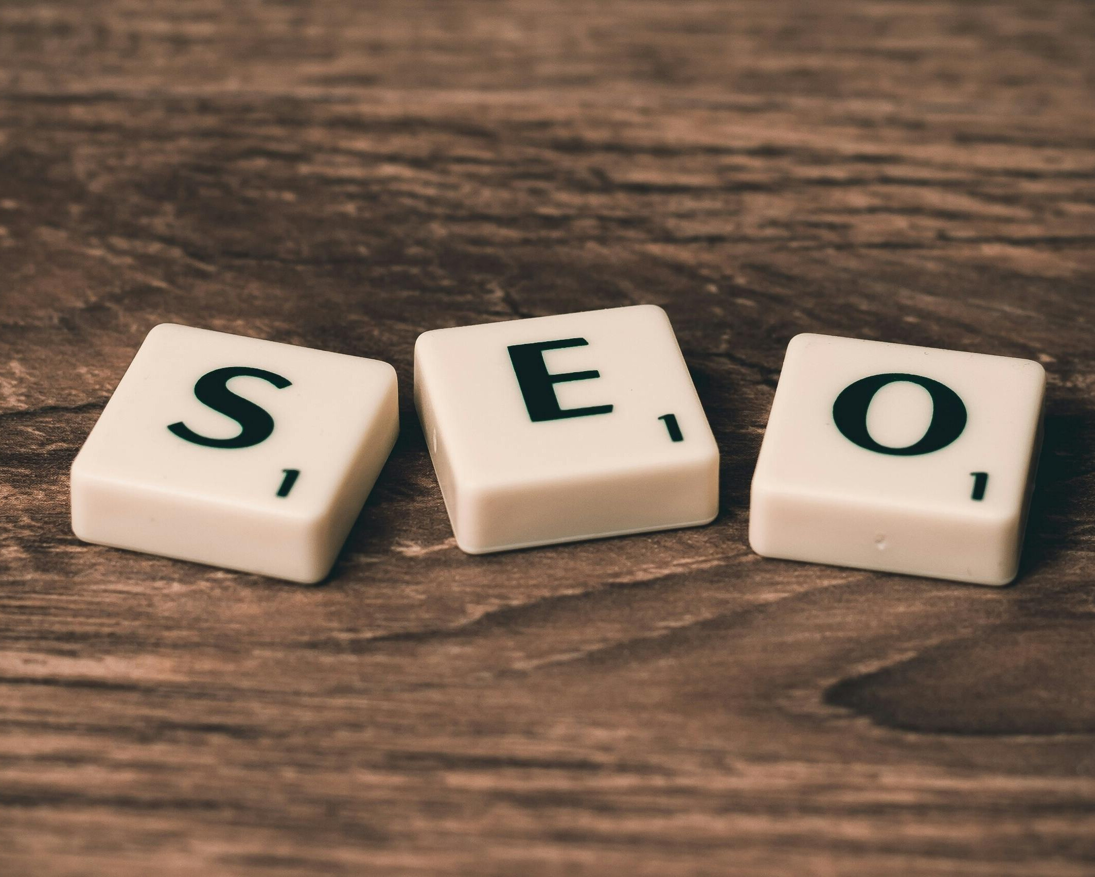 Close-up of white letter tiles spelling “SEO” on a wooden surface, symbolizing one of the core technical skills in digital marketing.